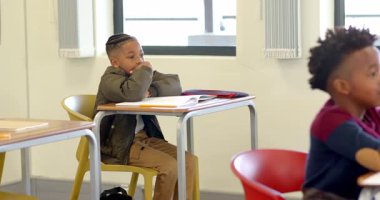 Okulda, masada oturan genç bir çocuk, dikkatle sınıfta dinliyor. Eğitim, okula dönüş, öğrenme, öğrenme, çocukluk, konsantrasyon