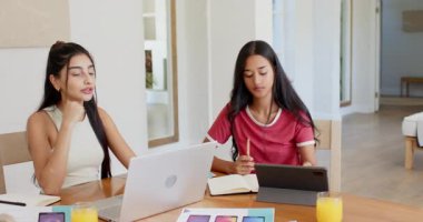 Çeşitli bayan arkadaşlar evde dizüstü bilgisayar açıyor ve akıllı telefon modellerine işaret ediyor, kavramları inceliyor. İşbirliği, akıl hocalığı, yaratıcılık, modern, çalışma alanı, ilham, beyin fırtınası