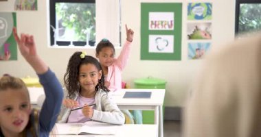 Okulda, gülümseyen kız sınıfta el kaldırıyor, katılmak için sabırsızlanıyor. Eğitim, öğrenme, katılım, okula dönüş, çocukluk