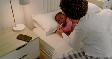 Afrika kökenli Amerikalı anne doktoru aramadan önce yatak odasında termometresi olan ateşli kızıyla ilgileniyor. Bakım, bakım, sağlık, konfor, sıcaklık, aile, bakım