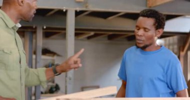 Ahşap dükkanında, kalem ve sütunlarla, kopyalama alanında yol gösteren Afro-Amerikan erkekleri. İşçilik, akıl hocalığı, işbirliği, endüstriyel, dayanıklı, mesleki, beceri