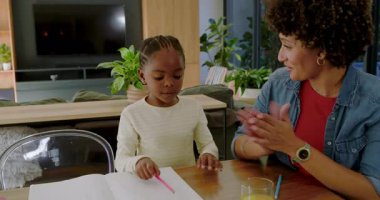 Çeşitli anne ve kız sayıyor, deftere yazıyor, parmaklarını tutuyor ve masada beşlik çakıyor. Aile, eğitim, öğrenme, bağlanma, çocukluk, etkileşim, yerli