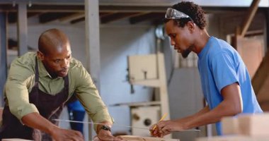 Kalem ve gözlüklerle marangozluk atölyesinde çalışan Afro-Amerikan iş arkadaşları. Sanatçılık, işbirliği, sanayi, işyeri, araçlar, doku, sanayi