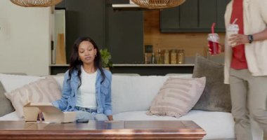 Kanepede oturan Afro-Amerikalı çift, film gecesi için buzlu içeceklerle içeri giren partnerleri. Romantik, samimiyet, rahatlık, konfor, modern, yaşam tarzı, bağlantı