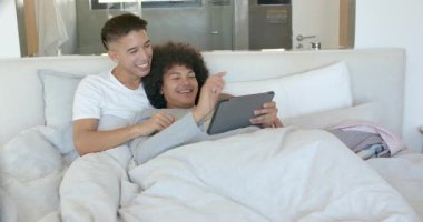 Yatak odasında iki adam tablet ekranı tıkırdatıyor ve içeriği keşfederken ortağının eline rehberlik ediyor. Romantizm, samimiyet, bağlantı, rahatlama, rahat, modern, şefkat