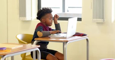 Sınıfta dizüstü bilgisayar kullanan Afrikalı Amerikalı çocuk, okulda öğrenme ve daktilo notlarına odaklanıyor. Eğitim, teknoloji, öğrenim, dijital