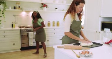 Çeşitli bayan arkadaşlar mutfak adasına tepsi yerleştiriyor, un serpiyor, ekmek yoğuruyor ve gülüyorlar. Aşçılık, işbirliği, ev, sıcaklık, doğal, neşeli, aşçılık