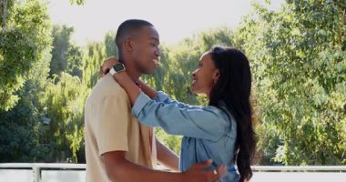 Afrika kökenli Amerikalı çift balkonda kucaklaşıp alınlarına dokunarak sevgiyi ifade ediyorlar. Romantizm, şefkat, bağ, doğa, açık hava, şefkat, uyum.