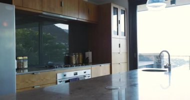 Modern mutfak mermer ada, ahşap dolaplar, cam kavanozlar, kolye ışıkları, teras manzarası. Lüks, çağdaş, zarif, minimalist, parlak, şık, ev