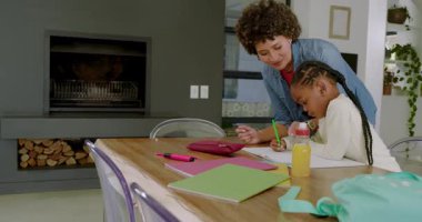 Ev ödevi için dizüstü bilgisayar sağlamadan önce Afrika kökenli Amerikalı bir anne kızına masada dinlenmesi için rehberlik ediyor. Aile, destek, eğitim, yetiştirme, ev, danışmanlık, kaynaşma