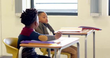 Sınıfta, masalarda yazı yazan çok ırklı çocuklar, ödevlerine konsantre oluyorlar. Eğitim, odaklanma, öğrenme, öğrenim, çok ırklı çocuklar, akademik