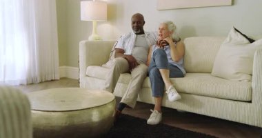 Son sınıf çifti kanepede fincanla oturuyor, sohbet ediyor ve evde birbirlerine sarılıyorlar. Arkadaşlık, samimiyet, sıcaklık, rahatlama, memnuniyet, sükunet, birliktelik.