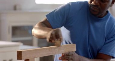 Tahta tahtaları, atölyeye dayanan Afro-Amerikan bir adam, güvenlik gözlükleri ve fotokopi alanı var. Zanaatkar, marangozluk, işçilik, inşaat, işçilik, yenileme, marangozluk.