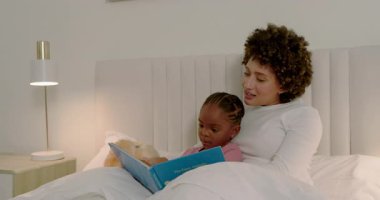 Çeşitli anne ve kız çocukları oyuncak ayıyla yatakta mavi kitap açıyor, resim okuyor ve kaynaşıyorlar. Aile bağları, yetiştirme, hikaye anlatma, konforlu, eğitici, hassas, özen gösterme