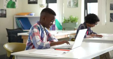 Sınıfta dizüstü bilgisayar ve tablet kullanan çok ırklı öğrenciler, okul ödevlerine odaklanıyorlar. Teknoloji, eğitim, dijital, öğrenim, cihazlar