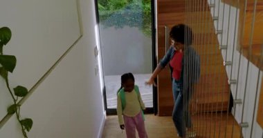 Çeşitli anne ve kız çocukları eve sırt çantalarını açıp atıştırmak için buzdolabından meyve suyu alıyorlar. Aile, yerli, yaşam tarzı, modern, iç mekan, yetiştirme, her gün.