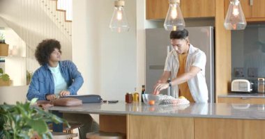 Çeşitli erkek arkadaşlar geliyor, meyve paketlerini açıyorlar, mutfak adasında laptop açıyorlar, tezahürat yapıyorlar. İşbirliği, dostluk, modern, canlı, yaşam tarzı, eğlence, iç mekan