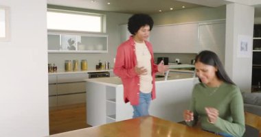 Mutfakta konuşan bir adam, masada ağlayan Hintli bir kadını teselli etmek için mendil uzatıyor. Duygusal, destek, arkadaşlık, teselli, samimiyet, modern, yaşam tarzı.