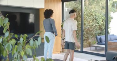 Warrior II 'den çeşitli erkek arkadaşları denge için evdeki minderlerde yoga pozu veriyor. Fitness, sağlık, farkındalık, uyum, sükunet, ev, modern