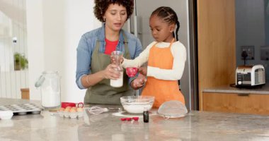 Çeşitli anne ve kızlar yumurta açıyor, süt döküyor, mutfak adasında kek hamuru karıştırıyor. Aile, yemek pişirme, aşçılık, aile içi, gelenek, ev, bağ