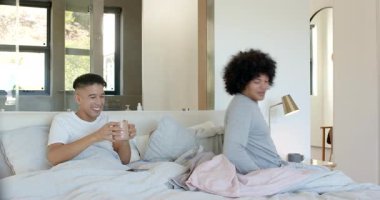 Çeşitli erkek partnerler kahve fincanı alıyor, yatakta kahve yudumluyor, akıllı telefon ekranı izliyor. Samimiyet, rahatlama, rahatlık, rahatlık, sıcaklık, bağlantı, sabah