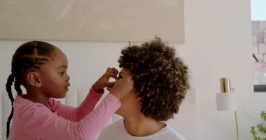 Çeşitli anne ve kız çocukları yatağa tırmanıyor gözlerinin etrafına kırmızı boya sürüyor bağlanmak için sarılıyorlar. Aile, yakınlık, yakınlık, şefkat, sanatçılık, sıcaklık, samimiyet.