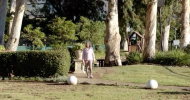 Yaşlı bir kadın çitten çıkıyor, tarladan geçiyor, egzersiz yapmak için çitlere bakıyor. Açık hava, doğa, refah, boş zaman, dinlenme, manzara, gelişigüzel