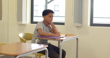 Okulda, elinde kalem olan bir çocuk, dikkatle masasını dinliyordu. eğitim, öğrenme, sınıf, çocukluk, öğrenci, okula dönüş