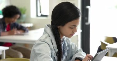 Sınıfta işe odaklanan bir kız, arka planda yürüyen bir bayan öğretmen, okulda. Eğitim, öğrenim, akademi, okul, öğrenim, öğretim