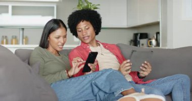 Çeşitli çiftler, gri kanepede akıllı telefon ve tablet değiş tokuş ederek ve gülerek içeriği paylaşıyorlar. Çağdaş, samimi, canlı, sıcak, neşeli, samimi, yaşam tarzı