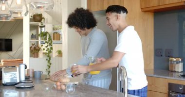 Erkek arkadaşlar mutfak adasında kahvaltı hazırlıyor meyve suyu dolduruyor, tost yapıyor ve avokado dilimliyor. İşbirliği, yaşam tarzı, modern, sıradan, kırsal, neşeli, sosyal