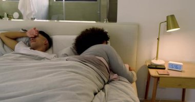 İki adam yatak odasındaki gri yorganın altında oynaşıyor alarm sesi duyuyor, saati susturuyor ve geriniyor. Romantizm, samimiyet, sabah, rahatlama, rahatlık, modern, minimalist