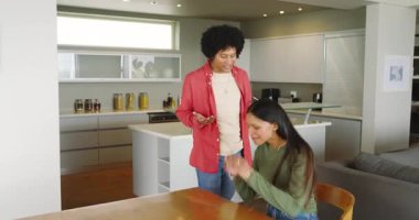 Bir çift duygusal bir konuşma yapıyor ve erkekler mutfakta nişan yüzüğü teklif ederken masada oturuyor. Romantizm, samimiyet, bağlantı, kutlama, bağlılık, modern, samimi