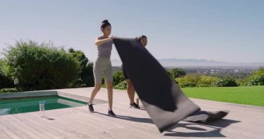 Egzersiz öncesi esnemeye başlarken çeşitli bayan arkadaşlar güneşli güvertede yoga minderlerini açıyorlar. Açık hava, fitness, yaşam tarzı, refah, uyum, arkadaşlık, doğal