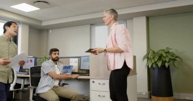 Doğu Asyalı çalışanlar dosyalarla girdikten sonra çeşitli iş arkadaşları raporları inceliyor. İşbirliği, takım çalışması, veri analizi, profesyonel, modern, iletişim, geç dönem toplantısı