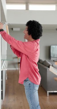 Dikey video: Ortağın yardımıyla evdeki boş duvara çivi çakan adam. Ev geliştirme, diy, iç tasarım, işçilik, işbirliği, modern dekor, dikey video