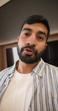 Dikey video: Hintli bir adam telefonda konuyu açıklayıp el sallayarak odaya giriyor. Profesyonel, modern, gündelik, kendinden emin, iletişim, yaşam tarzı, dikey video