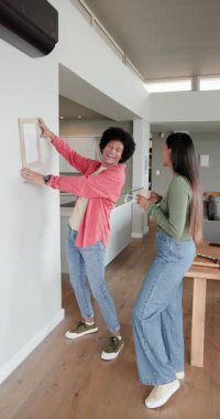 Dikey video: Çeşitli çiftler evdeki duvarı gösterdikten, çerçeveyi hizaladıktan ve kucaklaştıktan sonra tepki veriyorlar. İç, ev, dekor, yaşam tarzı, modern, rahat, dikey video