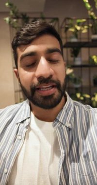 Dikey video: Kamera kaydıyla, Hintli adam saksı bitkilerinin arasında konuşuyor ve fikirleri vurguluyor. Stüdyo, sağlık, yeşillik, gündelik, çağdaş, ev ofisi, dikey video