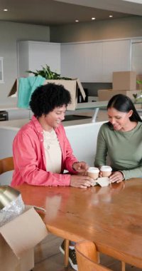 Evin içindeki masaya kahve getiren, yudumlayan ve gülerken tavanı işaret eden bir çift. Rahat, evcil, yaşam tarzı, çağdaş, neşeli, sıradan, dikey video