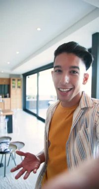 Dikey video: Akıllı telefonu tutmak, oturma alanını sunan adam, el kol hareketi, oturma ve göz kırpma. Modern, gündelik, yaşam tarzı, iletişim, ev, ifade, dikey video