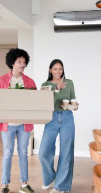 Dikey video: Ev anahtarlarını almak, ellerinde kahve tepsisi tutan Hintli çift ve evde kutuları boşaltmak. Taşıma, boşaltma, yenileme, yaşam tarzı, çağdaş, mutluluk, dikey video