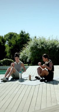 Dikey video: Çeşitli kadın arkadaşlardan sonra ağırlık kaldırma, paspas paketleme, güverteden çıkma. Fitness, yoldaşlık, canlılık, açık hava, aktif giyim, su, dikey video