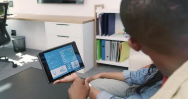 Ev ayarlarını ayarlamaya çalışan Afro-Amerikan çift tableti kanepeye vurup gülümsüyor. Teknoloji, akıllı ev, boş zaman, modern, etkileşim, rahat, yaşam tarzı.