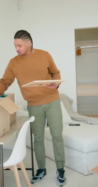 Dikey video: Çift olarak taşındıktan sonra bavulları açıp yatak odasını lamba çerçeveli battaniyeyle süsledikten sonra. Konut, işbirliği, minimalizm, iç mekan, yenileme, yaşam tarzı, dikey video