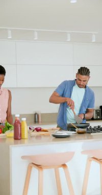 Dikey video: Mutfak adasında değişik çiftler jest yapıyor, soğan doğruyor ve yemek pişiriyor. Aşçılık, işbirliği, aşçılık, yerli, çağdaş, yaşam tarzı, dikey video