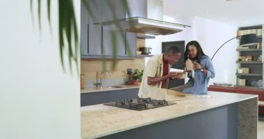 Afro-Amerikalı bir çift mutfakta yemek paketini açarken çubuk örnekleme ve ısırık paylaşımı yapıyor. Romantik, sıradan, çağdaş, rahat, otantik, neşeli, minimalist