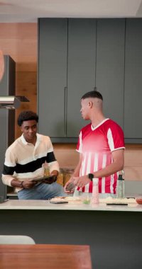 Dikey video: Tablet tarifini takip eden erkek arkadaşlar tezgahta biber düzenleme tahtasını sallıyorlar. Aşçılık, işbirliği, modern, yaşam tarzı, aşçılık, hazırlık, dikey video