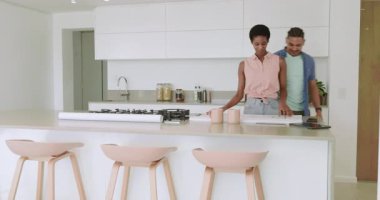 Mutfak adasına kahve kupası taşıyan çeşitli çiftler, mutfak planlarını açıyorlar, tablet üzerinde inceleme yapıyorlar. Çağdaş, işbirliği, iç mekan, ev, planlama, yenilikçi, yenileme