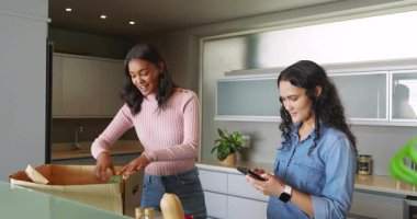 Mutfak adasında alışveriş yapan çeşitli bayan oda arkadaşlarını akıllı telefonlar ve sebzelerle paketliyorum. Aşçılık, arkadaşlık, modern, yaşam tarzı, gündelik, sağlıklı, yerli